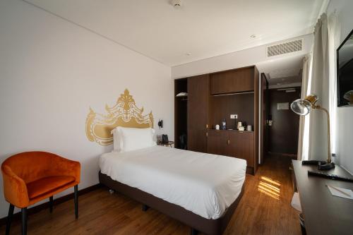 1 dormitorio con 1 cama blanca y 1 silla naranja en Palacio Santa Catarina Hotel, en Angra do Heroísmo