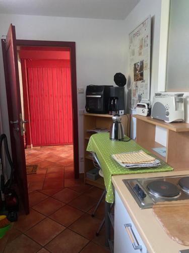 a kitchen with a red door and a table with a green table cloth at Wassermühle in Rheine
