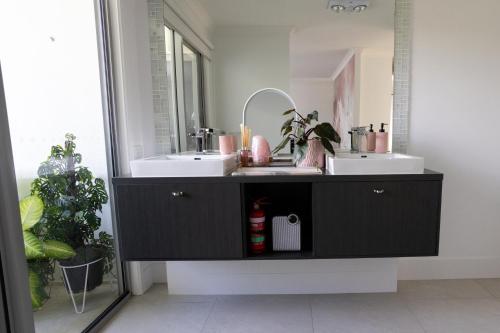 een badkamer met 2 wastafels en een spiegel bij Serenity Cove luxe retreat in Maroochydore