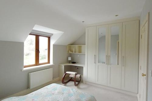 Habitación blanca con cama y ventana en Luxurious West Cork holiday home, en Bantry