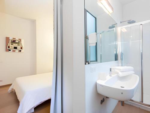 a white bathroom with a sink and a bed at The Apartment at Spanish Steps in Rome