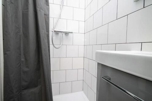 a white tiled bathroom with a shower and a sink at 02 Chambre avec lit double et sdb privé Wifi in Saint-Denis