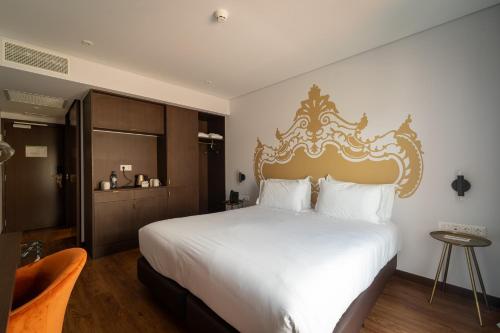 a bedroom with a large white bed with a gold headboard at Palacio Santa Catarina Hotel in Angra do Heroísmo