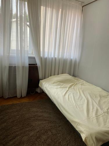 a bed in a room with white curtains and a window at Apartman NB in Sarajevo