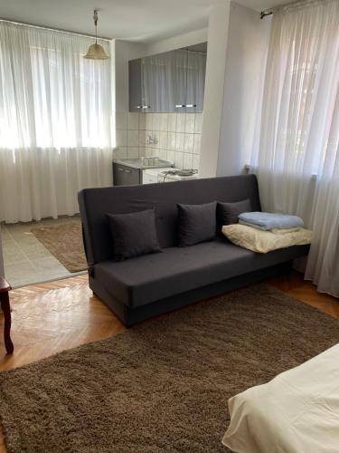 a black couch in a living room with a kitchen at Apartman NB in Sarajevo