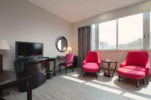 順德的住宿－佛山冠新酒店，酒店客房配有红色椅子、书桌和电视。