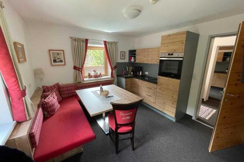 eine Küche und ein Wohnzimmer mit einem Tisch und roten Stühlen in der Unterkunft Wohnung Grief 143- Naviser Huette in Navis