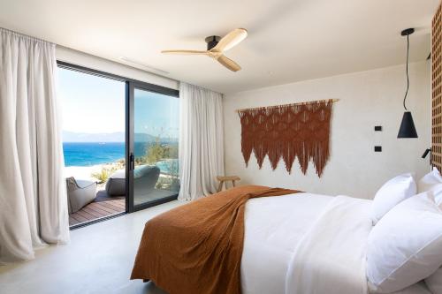 a bedroom with a bed and a large window at KOIA All - Suite Well Being Resort - Adults Only in Agios Fokas