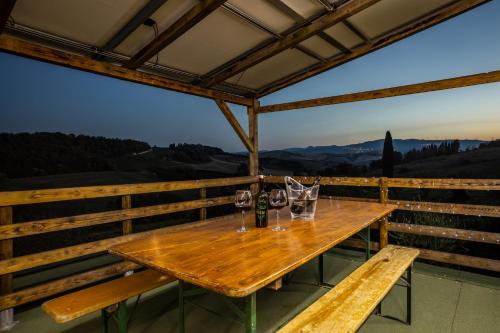a wooden table with glasses of wine on a balcony at Sole Verde green house in Terricciola