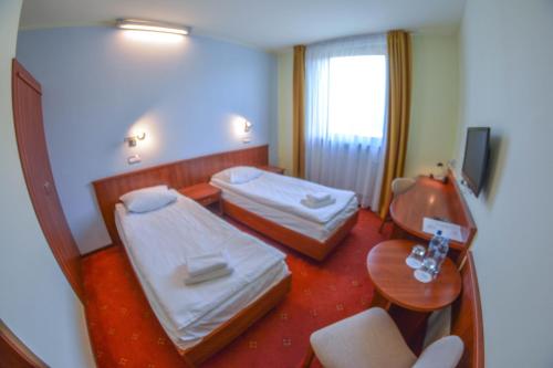 a hotel room with two beds and a table at Hotel Neo in Tarnowskie Góry