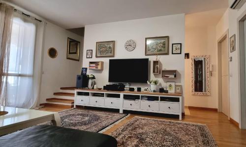 a living room with a television on a white cabinet at Tuscan Gallery House in Grosseto