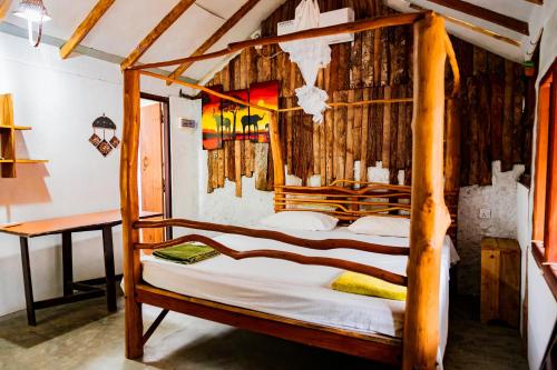 1 dormitorio con cama de madera con dosel en una habitación en Valampuri Kite Resort en Kalpitiya