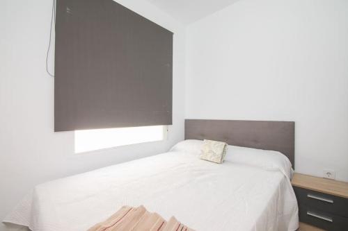 a bedroom with a white bed and a window at La Caracola - Espíritu libre A/A in El Altet