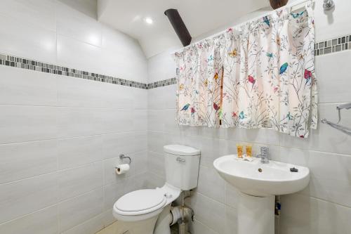 La salle de bains blanche est pourvue de toilettes et d'un lavabo. dans l'établissement Country Rose, à Hluhluwe