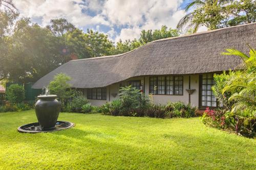 a house with a large vase in the yard at Country Rose in Hluhluwe