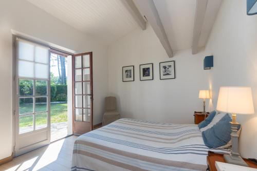 - une chambre blanche avec un lit et une porte coulissante en verre dans l'établissement La Kayola, à Soorts-Hossegor