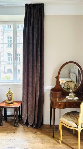 une fenêtre avec un rideau, une table et un miroir dans l'établissement Gîte Verrière Du Château BURRUS, à Sainte-Croix-aux-Mines