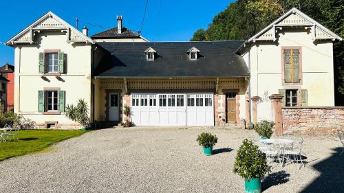 une grande maison blanche avec un garage dans l'établissement Gîte Verrière Du Château BURRUS, à Sainte-Croix-aux-Mines