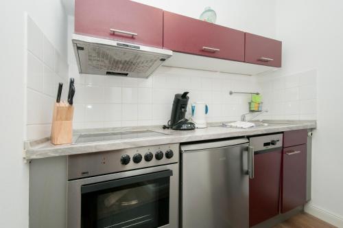 a kitchen with red cabinets and a stainless steel oven at Appartements in der historischen Deichstrasse contactless Check in in Hamburg