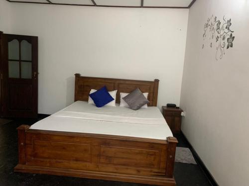 1 dormitorio con cama de madera y almohadas azules en LEO nature home, en Dodanduwa