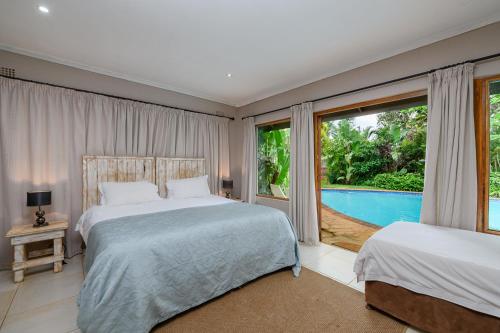 a bedroom with two beds and a view of a pool at Hlulala Guest House in Hluhluwe