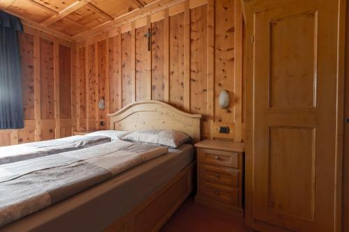 1 dormitorio con 1 cama y pared de madera en Appartamento Scialket en Livigno