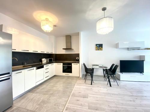 a kitchen with white cabinets and a table and chairs at Nature View Family Apartment in Braşov