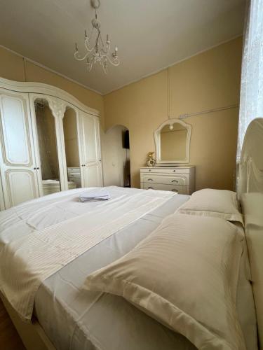 a bedroom with a large white bed and a chandelier at Eurasia hotel in Almaty