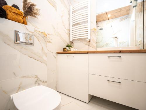 baño con aseo blanco y pared de mármol en OAK TREE Apartment en Dąbrowa Górnicza