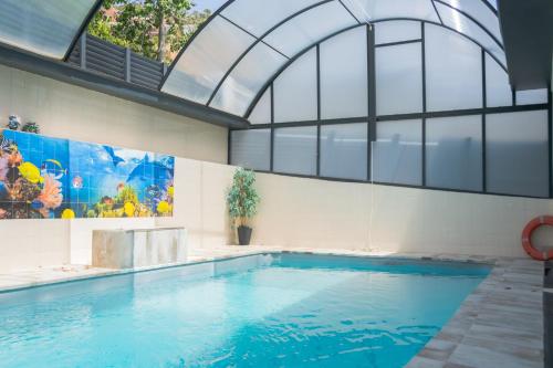 an indoor swimming pool with a large window and a large swimming pool at Luxurious Villa Marly II in Castelldefels