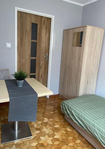a bedroom with a bed and a table and a door at Kwatery Pracownicze Noclegi Pokoje dla uczniów Kochanowskiego in Wysokie Mazowieckie