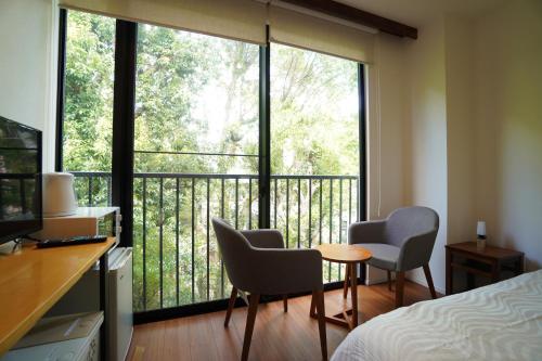a room with a bed and two chairs and a large window at Bird Hostel in Kyoto