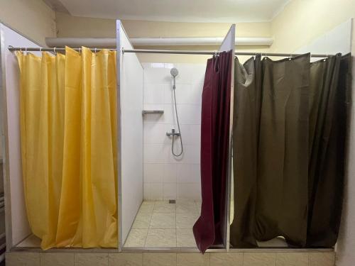 a bathroom with a shower with yellow shower curtains at Mouse House Hostel in Almaty