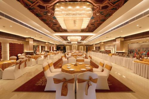 a banquet hall with white chairs and tables and a chandelier at Hotel Dara Royale in Amritsar