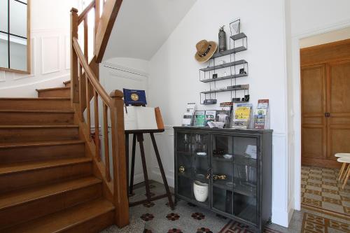 a hallway with a staircase with a cabinet and a shelf at L'Iliade - Chambres d'hôtes - B&B à Bouzy in Bouzy