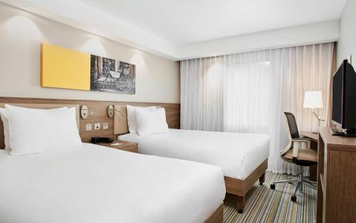 a hotel room with two beds and a desk at Hampton by Hilton Oxford in Oxford