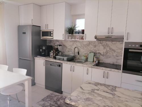 uma cozinha com armários brancos e electrodomésticos de aço inoxidável em Airport Apartment em Surčin