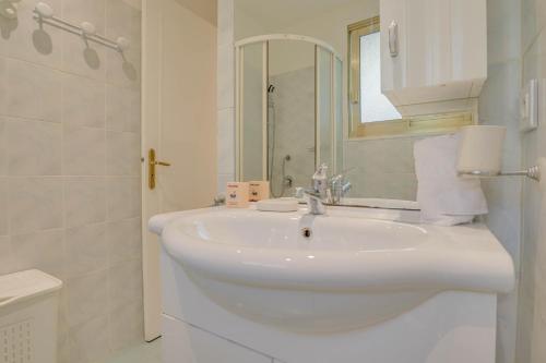 a white bathroom with a sink and a mirror at « Hawai » Proche Mer, Calme, Piscine in Menton