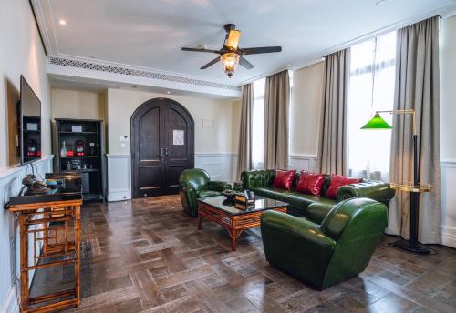 a living room with green leather furniture and a ceiling fan at Guangzhou Nansha Stone Inn in Guangzhou