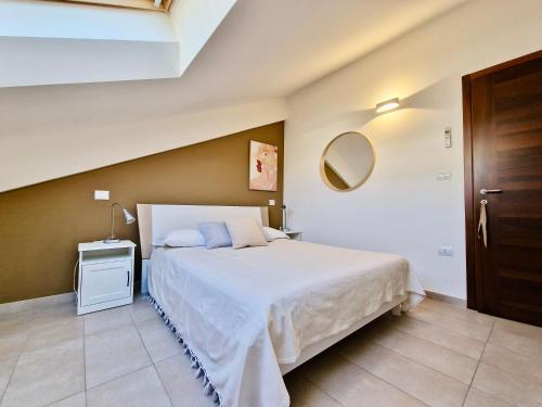 1 dormitorio con cama blanca y espejo en Casa Elena by TraMonti Apartments en LʼAquila