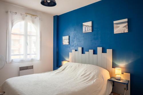 niebieska sypialnia z białym łóżkiem i oknem w obiekcie Appartement T2 entièrement rénové w mieście Saint-Cyr-sur-Mer