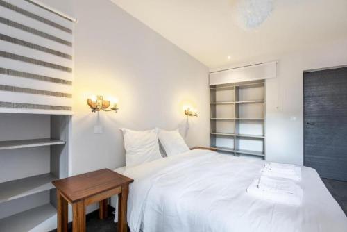 - une chambre avec un lit blanc et une table en bois dans l'établissement Le Romantique, à Annecy