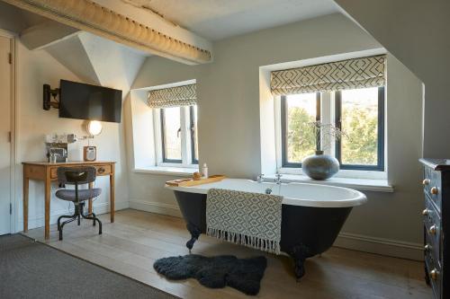 a bathroom with a tub and a desk and windows at Timbrell's Yard in Bradford on Avon