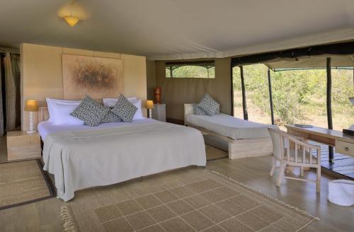 a bedroom with a large bed and a desk at Kicheche Valley Camp in Naboisho