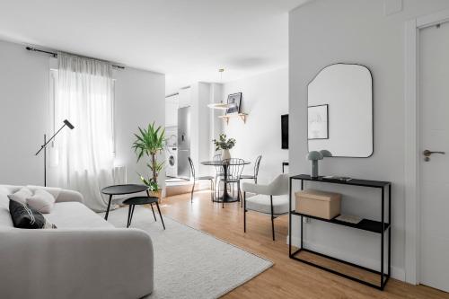 a white living room with a white couch and a table at Cozy 2 bedroom apartment with patio in Madrid