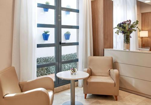 ein Wartezimmer mit zwei Stühlen, einem Tisch und einem Fenster in der Unterkunft NH Valencia Las Ciencias in Valencia