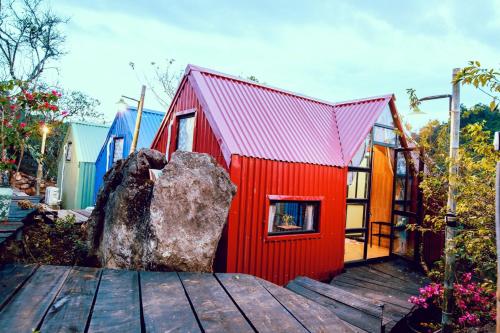 a red house with a rock on a wooden deck at Homestay Bản Búa in Mộc Châu