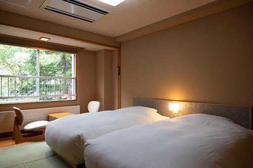 札幌的住宿－Hatagoya Jozankei Shoten-Adult Only，酒店客房设有两张床和窗户。