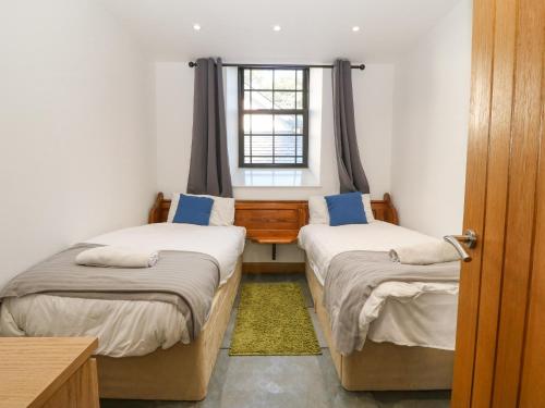 2 camas individuales en una habitación con ventana en Hen Gapel Seion en Caernarfon