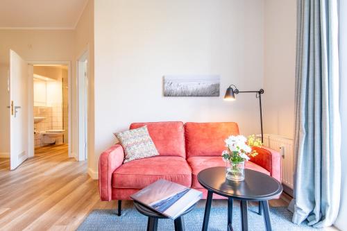a living room with a red couch and a table at Steger-Hüs Wohnung 02 in Rantum
